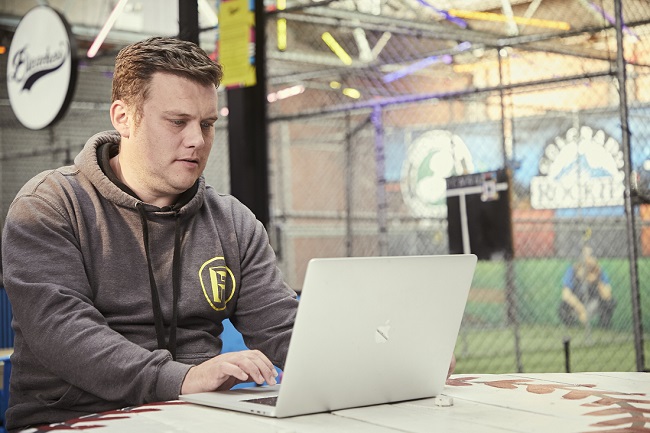 A man in a hoody uses a laptop in the activity bar that he runs
